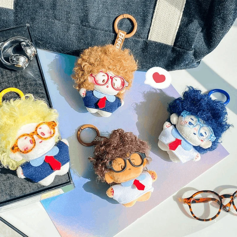 Four school-themed plush character keychains styled on notebooks and a bag
